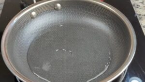 A Stainless Steel Pan with Water Heating on A Stovetop