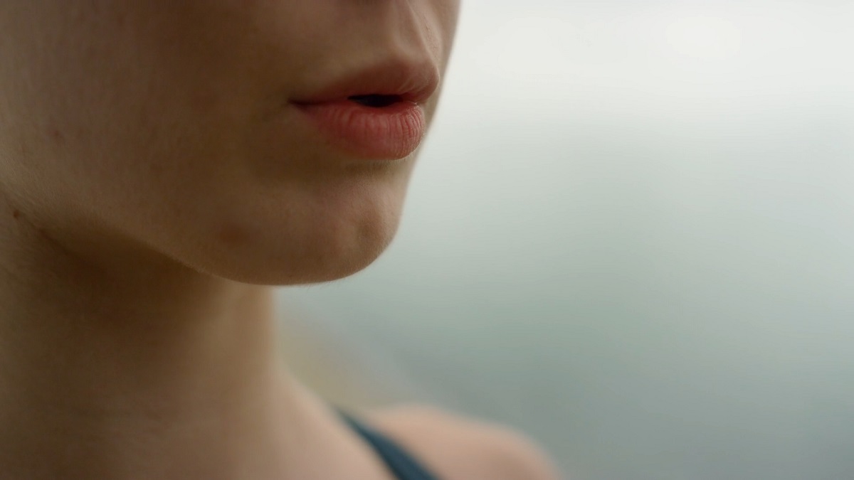 A close-up of a woman’s lips slightly parted, emphasizing natural breath and freshness, against a soft