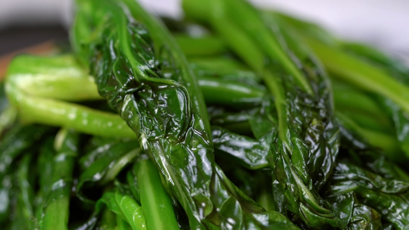 Close-Up of Freshly Cooked Gai Lan (Chinese Broccoli) with Glistening, Deep Green Leaves and Tender Stalks