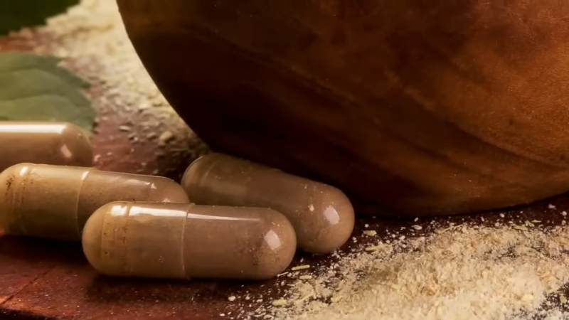 Ashwagandha Capsules Placed on A Wooden Surface with Powder Nearby