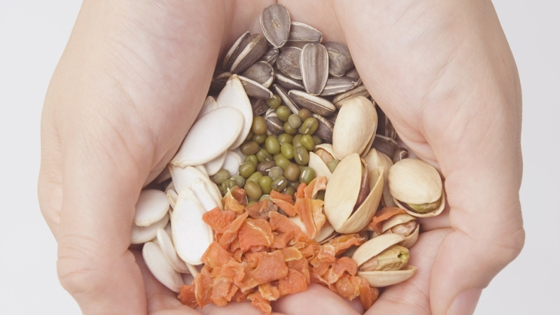 Hands holding a mix of seeds and nuts often used to support hormone balance and overall health